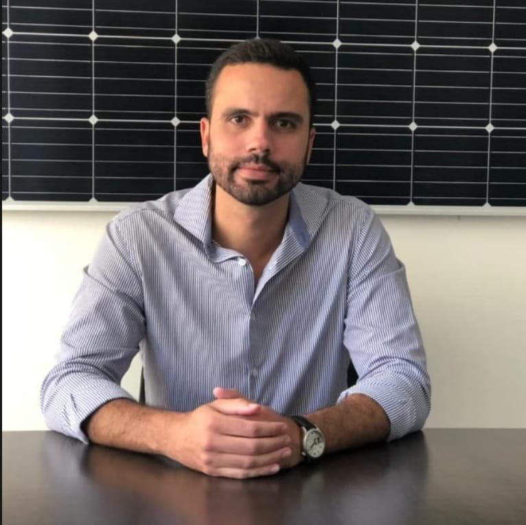 Fundador da SolarMarket diante de módulos fotovoltaicos